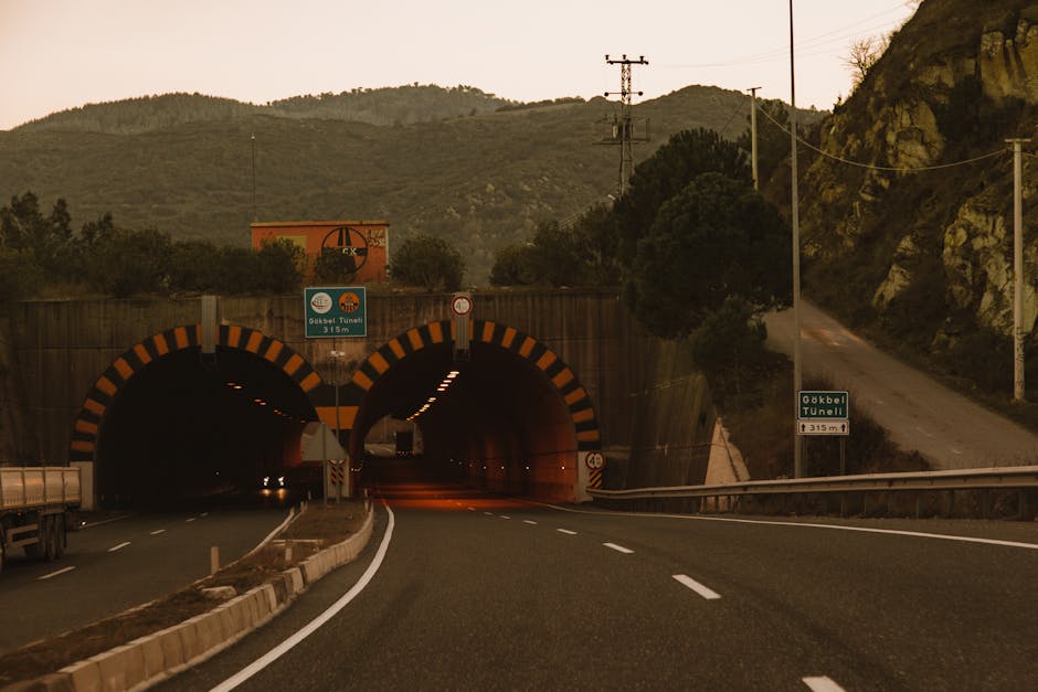 A captivating view of a mountain tunnel entrance surrounded by lush foliage at sunset.